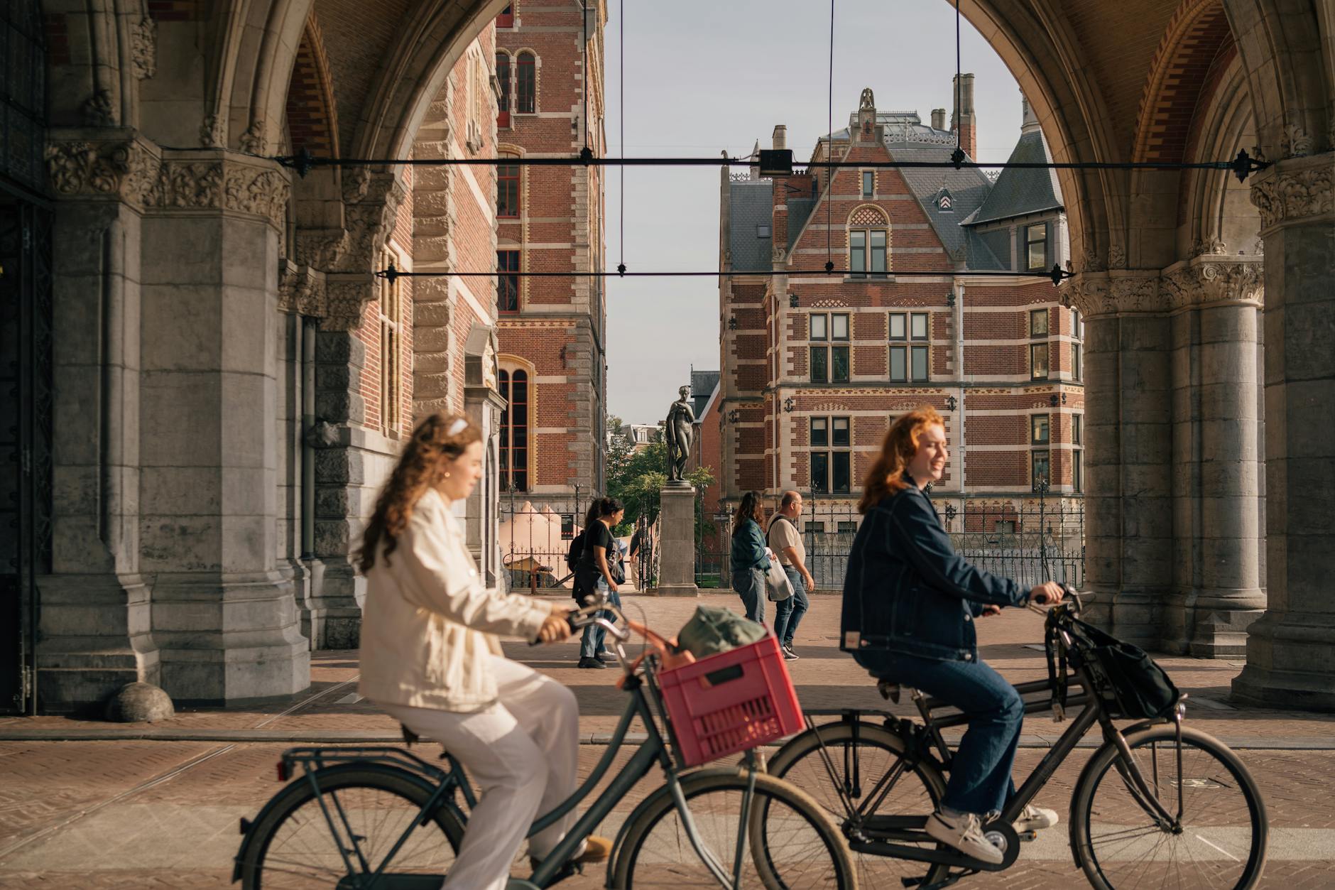 Kobiety na rowerach przejeżdżają pod zabytkową amsterdamską bramą