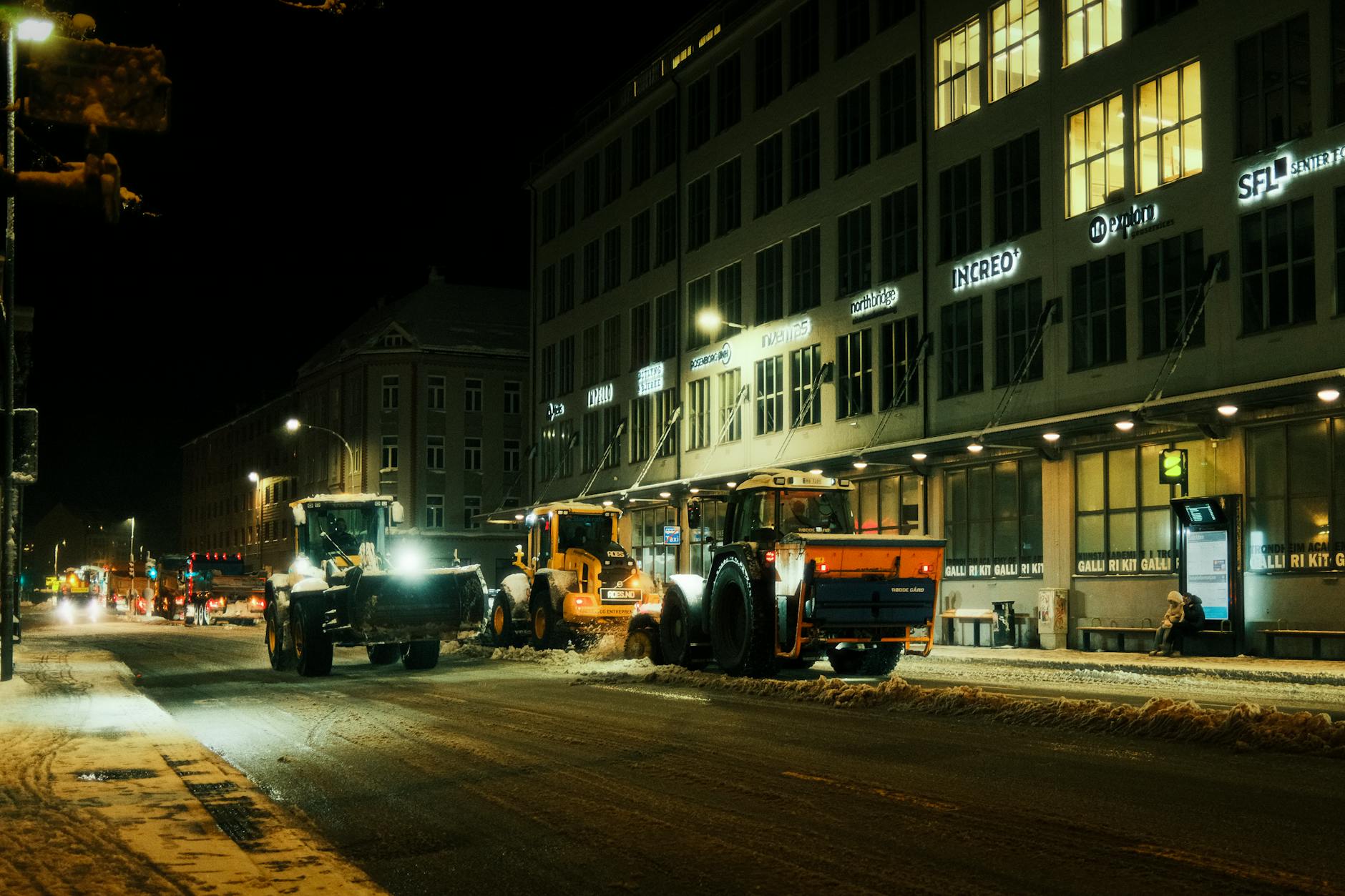 Pługopiarki odśnieżają miejską ulicę nocą zimą