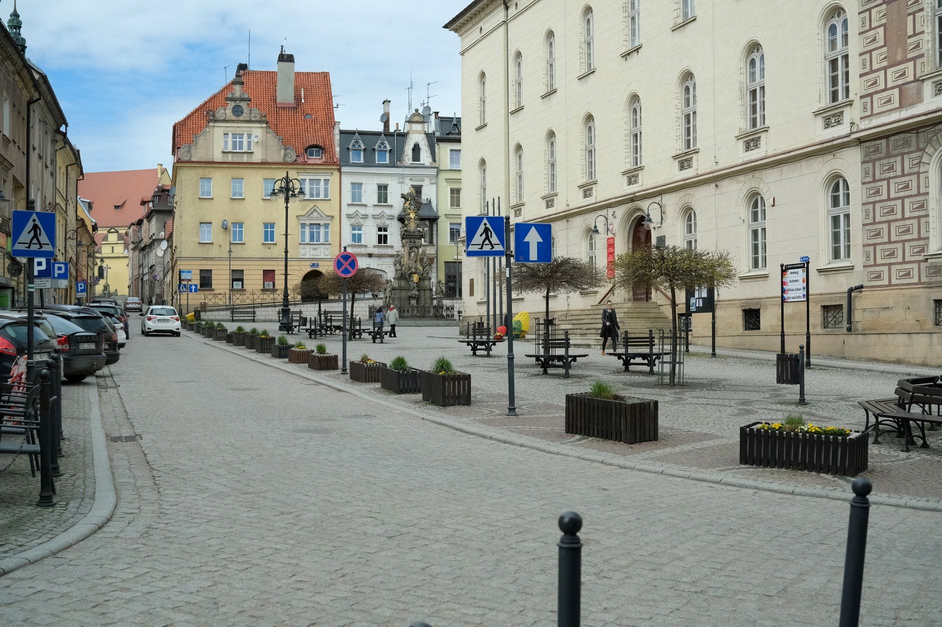 Zabytkowe kamienice i brukowany plac z ławkami w europejskim mieście