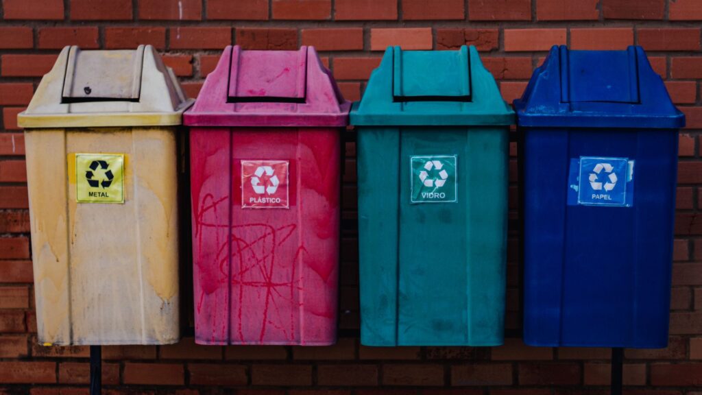 Kolorowe pojemniki do segregacji metalu, plastiku, szkła i papieru przy ceglanej